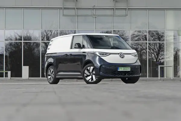 Dwukolorowy Volkswagen ID. Buzz 7 osobowy, zaparkowany przed nowoczesnym budynkiem z lustrzanymi oknami.