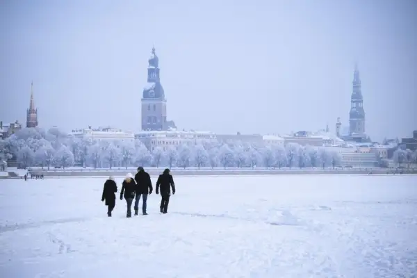 Familie spaziert über zugefrorene Daugava in Riga, Lettland im Winter. Die Stadt mit ihren Türmen ist im Schnee versunken.