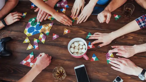 Hände legen bunte Spielsteine auf den Tisch. Ein gemütlicher Abend mit Zeit mit den liebsten Brettspiele.