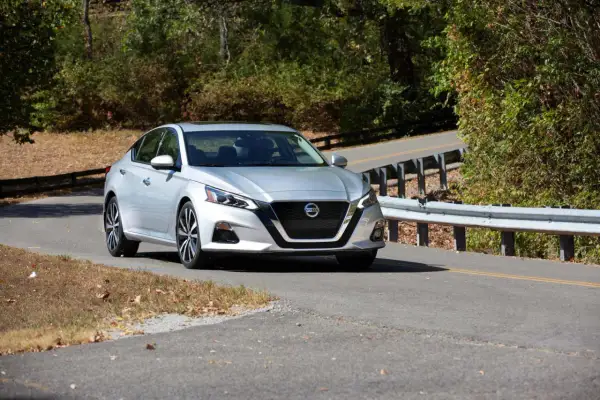 Srebrny Nissan Altima na krętej drodze, gotowy do przeniesienia własności samochodu.