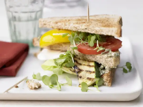 Ein saftiges, vegetarisches Sandwich mit gegrilltem Zucchini, Tomate, gelber Paprika und frischen Sprossen auf Vollkorntoast.