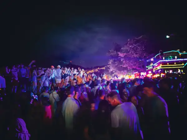 Stor folkmassa festar under neonljus på Koh Phangan, Thailand.