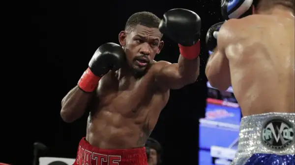 Jacobs boxer, Daniel Jacobs, throws a punch during a boxing match, sweat glistening on his muscular physique.