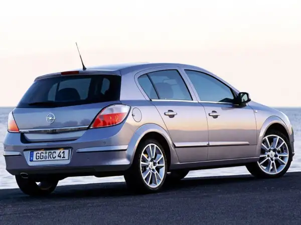 Srebrny Opel Astra H 1.6 benzyna z widokiem z tyłu, zaparkowany nad morzem.