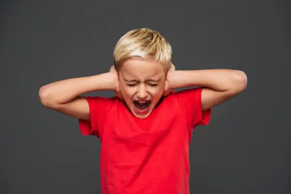 Bambino con capelli biondi, occhi chiusi e bocca spalancata, copre le orecchie con le mani. Rappresenta una crisi di rabbia nei bambini di 10 anni.