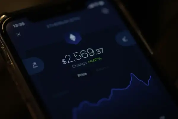 Na ekranie telefonu widać wykres i kwotę 2569,37 USD. Czy kryptowaluty są legalne? To pytanie nurtuje wielu inwestorów.