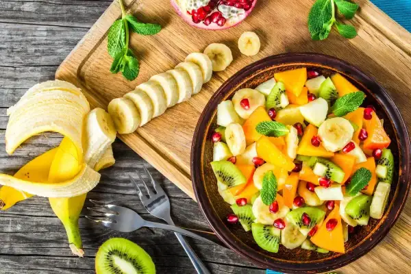 Kolorowa sałatka owocowa z kiwi, bananem, mango i granatem. Idealna na deser, zastanawiasz się, jaki sos do sałatki owocowej będzie najlepszy?