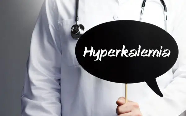 Lekarz w białym fartuchu ze stetoskopem trzyma czarną chmurkę z napisem "Hyperkalemia". Oznacza to podwyższony potas we krwi.
