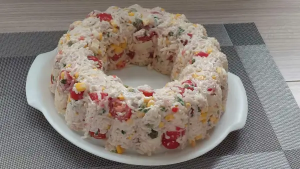 Salade de riz en forme de couronne, garnie de tomates cerises, maïs et persil.