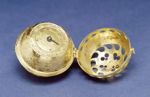Esfera dorada ornamentada de un primer reloj mecánico, abierta para mostrar su intrincado interior.