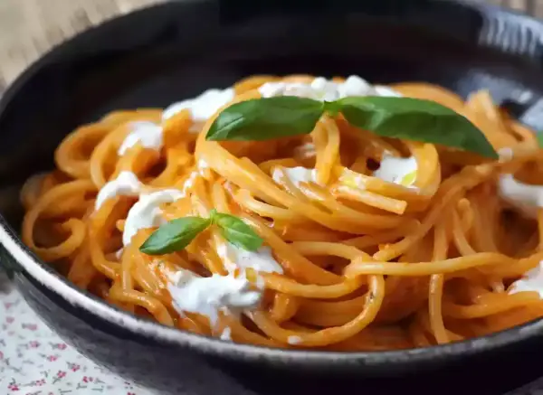 Spaghetti med krämig tomatsås och burrata, toppad med färsk basilika. En härlig pasta burrata-rätt.