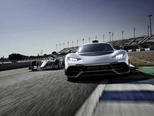 Wyścigowy bolid F1 i biały Mercedes-AMG Project One pędzą po torze.