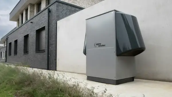 Une pompe à chaleur Alpha Innotec est installée près d'un bâtiment moderne. Elle fonctionne pour réguler la température, mais combien de temps tourne une pompe à chaleur par jour ?