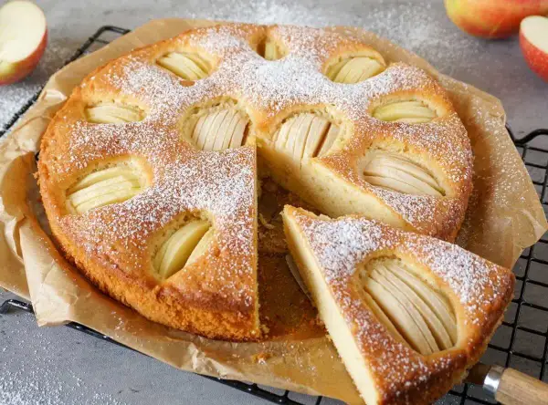 Omas weltbester Apfelkuchen, mit Puderzucker bestäubt und saftigen Apfelscheiben, wartet darauf, genossen zu werden.