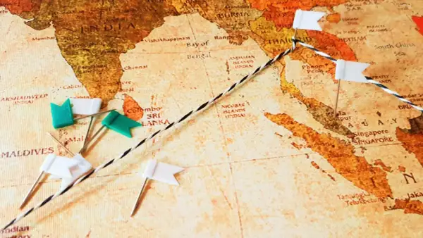 Eine Weltkarte mit Stecknadeln und einer Schnur, die eine Route markiert. Eine Mini-Weltreise beginnt in Indien und führt über die Malediven und Sri Lanka nach Südostasien.