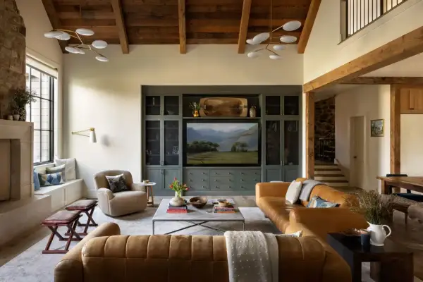 Cozy living room in a ranch style house featuring leather sofas, a stone fireplace, and a built-in entertainment center with a landscape painting.