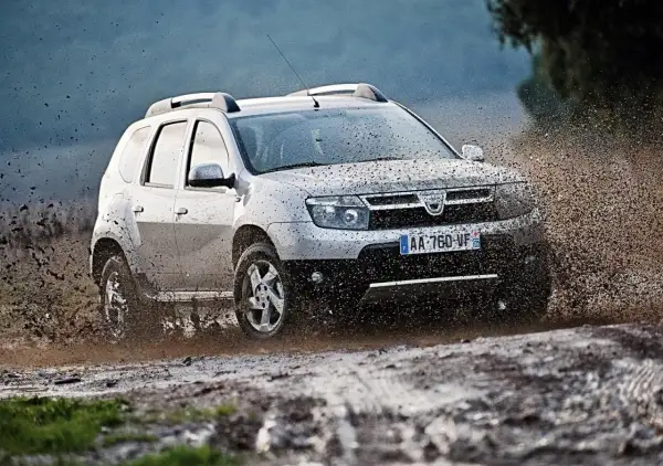 Srebrny Dacia Duster pruje przez błoto, pokazując, że to jedne z **aut tanich w utrzymaniu**, gotowe na każdą przygodę.