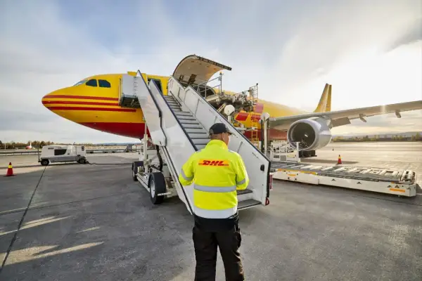 Pracownik DHL nadzoruje załadunek przesyłki lotnicze do samolotu.
