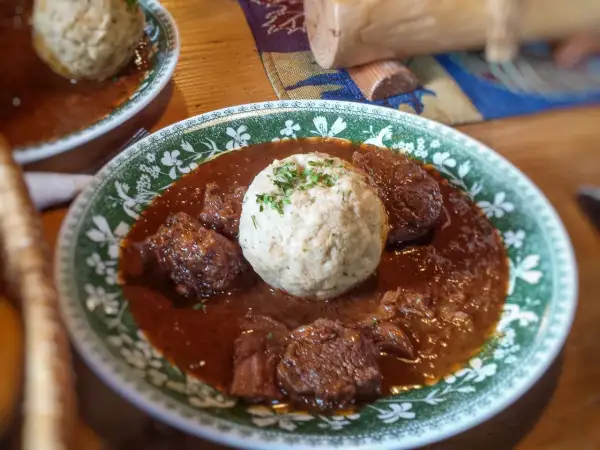 Herzhaftes Gulasch mit Klößen, ein klassisches Gulasch Rezept, serviert auf einem Teller mit grünem Muster.