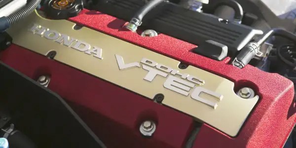 Złota pokrywa silnika Honda z napisem VTEC. Czerwone, teksturowane wykończenie dodaje sportowego charakteru.