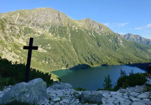 Czarny krzyż na skale, z widokiem na jezioro i góry. To nie najwyższy szczyt w Polsce, ale widok zapiera dech.