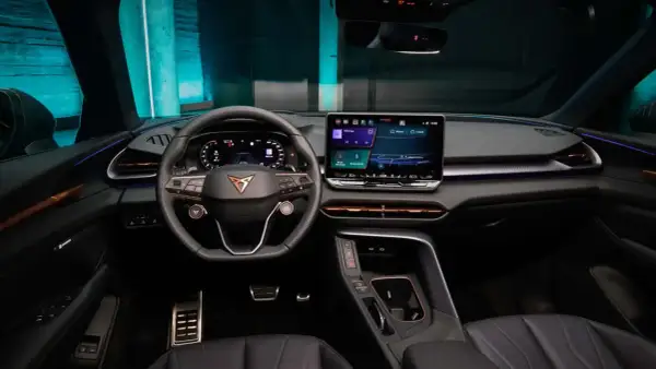 Interni moderni e tecnologici della Cupra Terramar, con ampio display centrale, volante sportivo e illuminazione d'ambiente.