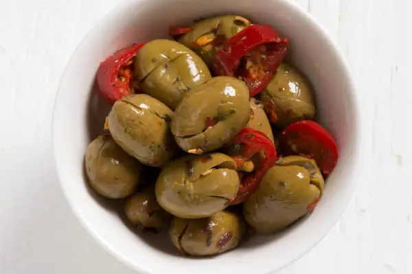 Olive verdi schiacciate con peperoncino rosso in una ciotola bianca. Perfette per un antipasto veloce, ecco come fare le olive verdi schiacciate.