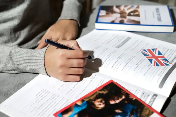 Osoba pisze w zeszycie z flagą Wielkiej Brytanii. Uczy się angielskiego, a akronim co to?