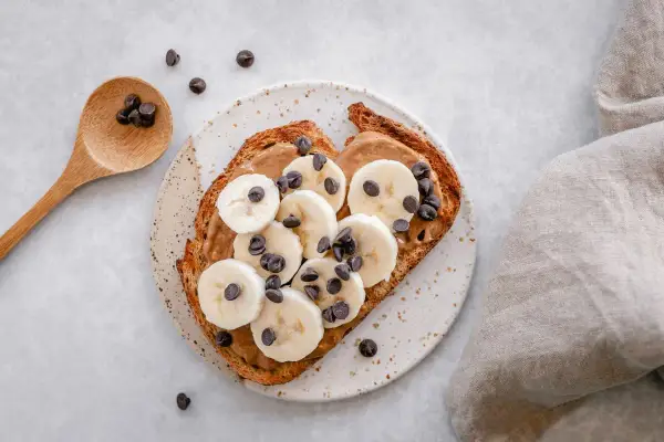 Tostada con mantequilla de maní, plátano en rodajas y chispas de chocolate. ¡Perfecta para merendar!