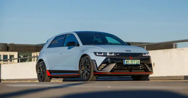 Sportowy Hyundai Ioniq 5 N w kolorze jasnoszarym z czerwonymi akcentami, zaparkowany na zewnątrz.