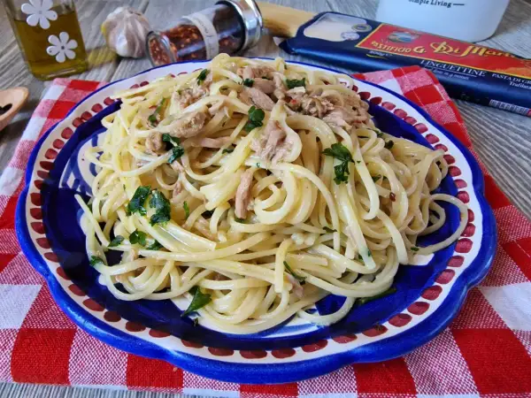 Un piatto di linguine con tonno e prezzemolo, condito con olio e peperoncino. Un classico della pasta al tonno in bianco, pronto per essere gustato.