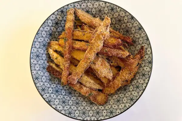 Bastoncini di melanzane impanate, un classico delle ricette della nonna, serviti in una ciotola decorata.