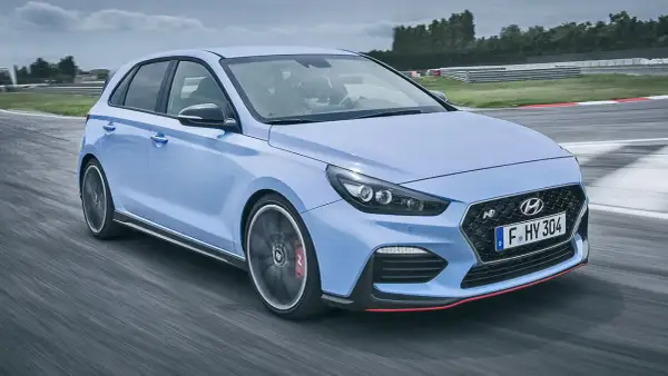 Un Hyundai i30 N azul compite en una pista, mostrando su potente motor y diseño deportivo.