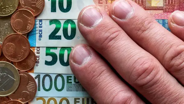 Dłonie na banknotach 10, 20, 50, 100 euro i monetach. To archiwum kursu euro.