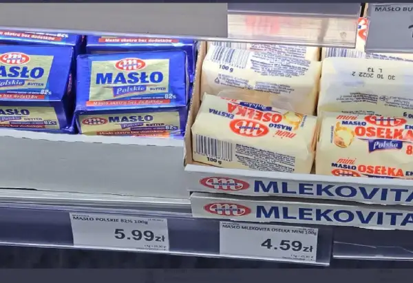 Na półce sklepowej widać opakowania masła. Jedno z nich, "Masło Polskie 82%", waży 100 gramów. Obok leżą mniejsze kostki masła "Osełka Mini" również po 100 gramów.