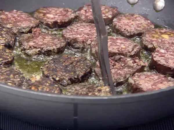 Rodajas de morcilla de Burgos dorándose en sartén con aceite burbujeante. Perfectas para tus recetas.
