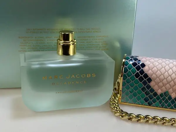 Flakon perfum Marc Jacobs Decadence Eau So Decadent obok ozdobnej torebki.