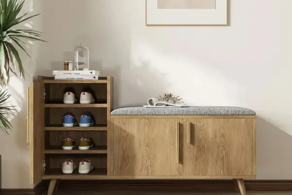 Stylish entryway decor ideas: a wooden shoe cabinet with a padded bench top, open shelves with shoes, and a decorative plant.