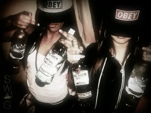 Två personer i fjortis stil med "Obey"-kepsar och Bacardi-flaskor.