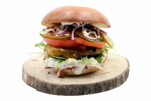 Soczysty burger z jalapeno, pomidorem, cebulą i ogórkiem na drewnianym plastrze.