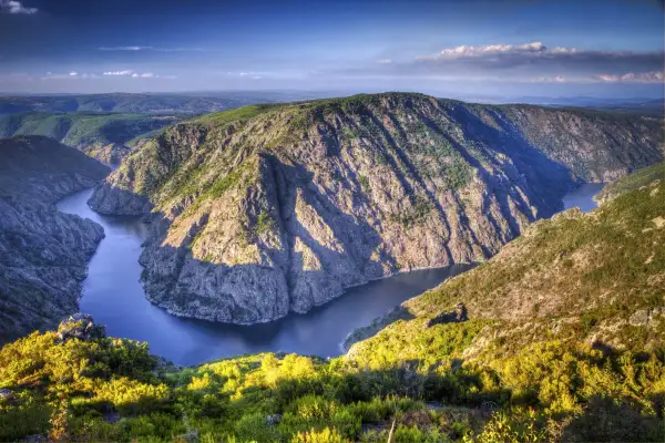 Majestuoso río serpentea entre escarpados acantilados cubiertos de vegetación, creando un paisaje impresionante en los cañones del Sil.