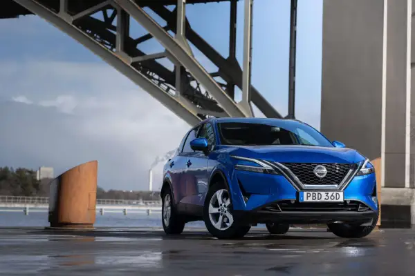 Blå Nissan Qashqai parkerad vid en bro. En spännande nissan qashqai test i en industriell miljö.