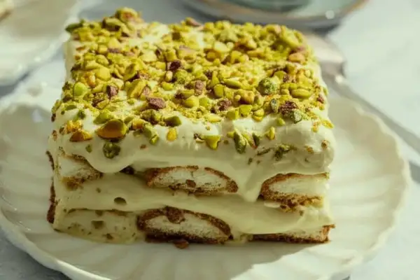 Un délicieux tiramisu pistache, superposé de biscuits et de crème onctueuse, le tout saupoudré de pistaches concassées.