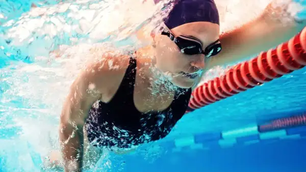 A swimmer in goggles and cap powers through the water. This image shows that boxers can swim, and do so with impressive strength and technique.