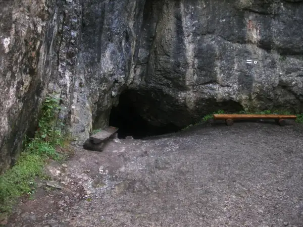 Wejście do jaskini w skale, obok ławka i kamienna ława. Tajemnicza dziura w górach, może w okolicach Zakopanego.