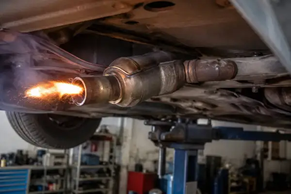 Ogień i iskry wydobywają się z rury wydechowej samochodu na podnośniku. To proces wypalania DPF.