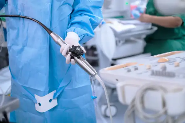 Przygotowanie do echo serca przezprzełykowe: lekarz w fartuchu i rękawiczkach trzyma sondę.