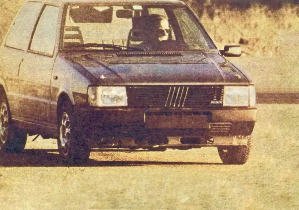 Ciemny Fiat Uno Turbo z kierowcą za kierownicą, gotowy do jazdy.