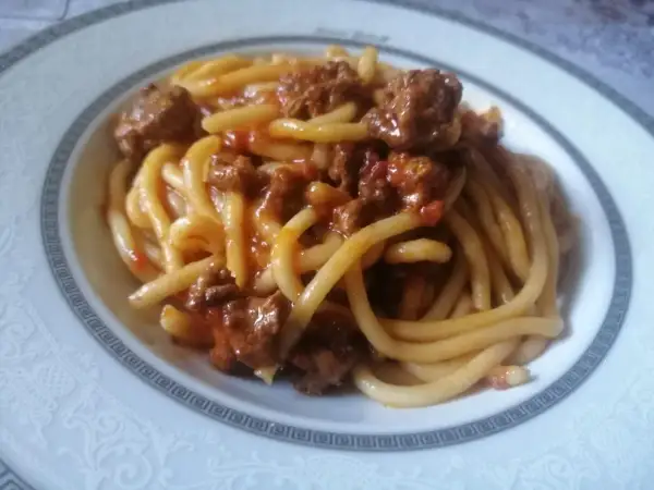 Pici fatti in casa conditi con un ricco ragù di carne, un classico della cucina toscana.