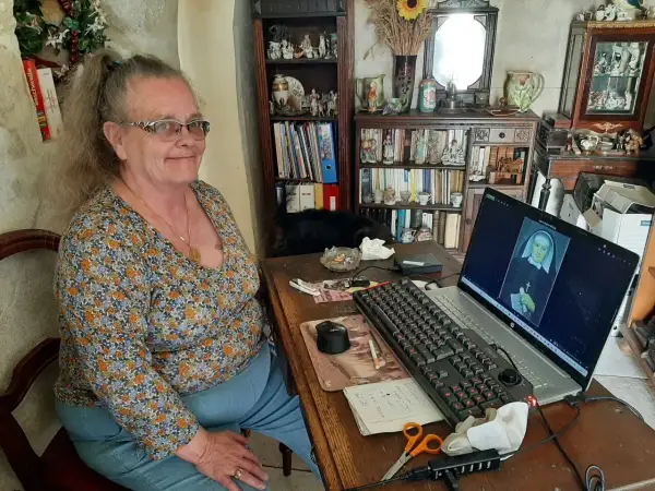Une femme consulte des archives en Sarthe sur son ordinateur, où s'affiche le portrait d'une religieuse.
